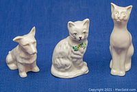 Front view of the three figurines (dog and two cats) placed on blue fabric background
