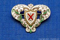 Front view of the enamel brooch showing detailed floral and shield design with white, green, and red enamel on sterling silver.