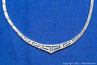 Close-up photo of the necklace's Greek key pattern and V-shaped centerpiece.