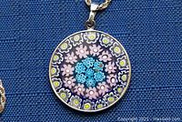 Close-up of the round pendant showing hand-painted floral designs.