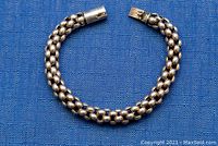 Full view of the 7.5 inch sterling silver bracelet laid flat on blue fabric background.