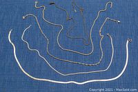 Five sterling silver chains laid out on fabric background showing variety of chain styles and lengths.