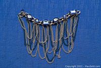Full view of the silver-tone belly dancing accessory showing blue glass stones and hanging chains against a blue background.