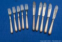 Ten flatware pieces (5 forks, 5 knives) laid out on blue fabric