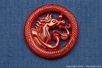 Close-up front view of the carved red jade horse medallion showing horse head inside circular border on blue background.