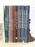 Photo showing 13 hardcover books of Canadian Art Sales Index arranged vertically, titles on spine visible with years from 1980-2001 and one Colonial art index book 2000-2001.