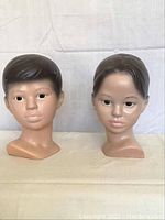Two mannequin heads, male and female, side by side showing front and three quarter views.