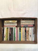 Box of paperback mystery and detective books laid flat, visible spines showing titles and authors including Agatha Christie