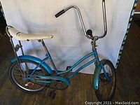 Side profile of light blue Speedo bicycle showing frame, white banana seat, rear wheel with chain guard, and pedals.