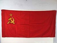 Full view of the red Soviet flag with gold hammer and sickle and star emblem from USSR, vintage condition with visible creases.