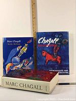 Three Marc Chagall first edition large books standing against a wall with a ruler for scale.