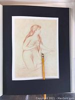Page from a large art book showing a pencil sketch of a nude female figure matted over a black page with pencil for scale.