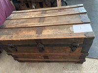 Closed view of the wooden antique trunk showing exterior and metal corner hardware