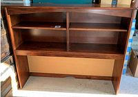 Photo of a dark brown wood hutch top with two shelves and a bulletin board backing, showing its storage compartments as empty and some surface scratches on wood.