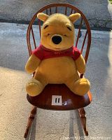 Large Winnie the Pooh stuffed animal sitting on wooden rocking chair showcase size and condition of toy and chair