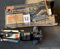 Photo of a Pro Lift heavy duty hydraulic service jack with its original box. The box is worn and has printed information on lifting capacity and safety.