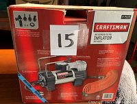 Craftsman inflator in its original box showing features and accessories included, coiled orange hose, and metal body.