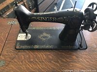 Close-up of Singer sewing machine with visible gold decorative detailing on black metal body.