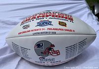 White commemorative football with New England Patriots logos and Super Bowl XXXIX details, scored Patriots 24, Eagles 21, dated February 6, 2005, Jacksonville FL. Marked limited edition 1 of 5000.