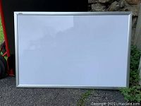 Clear image of a rectangular whiteboard with silver frame outdoors, showing full board surface and frame details.