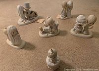 Image of six Precious Moments porcelain figurines arranged on carpet background, showing different character scenes.
