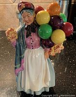 Front view of Biddy Pennyfarthing porcelain figurine showing colorful balloons and detailed clothing.