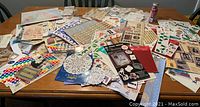 Photo showing a large table covered with assorted scrapbook sticker sheets and packages, featuring multiple themes such as sports, holidays, and family.