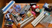 Photo of entire lot showing multiple scrapbooking cutting tools, paper trimmers, punches, scissors, and adhesive tape rollers on wooden surface
