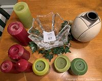 Lot including a clear glass decorative bowl, beige and black museum replica vase, and seven pillar candles in red and green.
