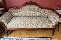 Full frontal view of the 19th century Rococo Revival carved walnut sofa with floral upholstery, showing detailed wood carvings and fabric pattern.