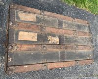 Top and side view of antique wooden trunk showing metal reinforcements and wear.