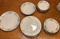 Top view of the dinner plates, lunch plates, bowls, and serving dishes arranged on a wood table.