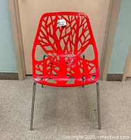 Front view showing tree branch patterned red plastic seat with chrome legs.
