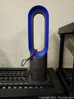 Front view of Dyson Hot+Cool bladeless fan heater in black and blue with power cord wrapped around.