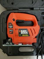 Top view of the Black & Decker variable speed jigsaw in its black plastic storage case, showing the orange tool body and labeling on the side.