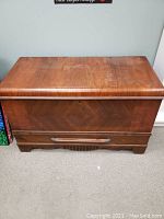 Front view of the closed vintage cedar chest showing wood grain and keyhole.