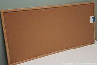 Photo showing the full cork bulletin board with light wooden frame on a table, shot from angle.