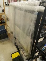 Two large rolls of clear plastic sheeting hanging on a rack, showing size and transparency of sheets.