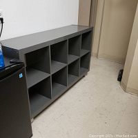 Front angle showing entire grey Kallax storage unit with eight open cubby holes in two rows of four.