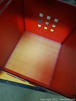 Interior bottom view of one red IKEA Lekman storage box showing the grid pattern and red plastic sides.