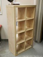 Front view of the beige IKEA Kallax shelving unit with 8 cubes in two columns and four rows.