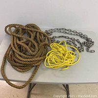 Photo showing the brown natural fiber rope, yellow synthetic rope, and metal chain laid out on a grey surface.