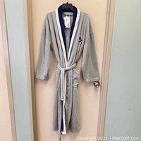 Full view of the grey fleece robe with blue and white trim, hanging on a door.