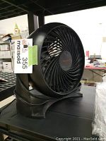 Side angle view showing the black circular fan head, Honeywell logo, and curved base with power cord wrapped around.