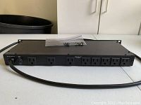 Rear view showing 8 AC outlets and the attached power cable, with mounting screws on top.