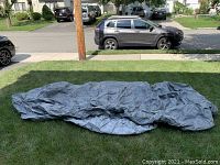 Full view of gray Budge car cover laid out on grass, showing overall size and condition.