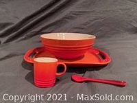 Front view of espresso mug, serving bowl and rectangular platter with spoon on dark fabric surface.
