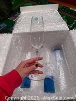 Hand holding a single clear champagne flute glass with long stem, showing size and clarity.