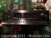 Front view of the black Onkyo surround sound receiver showing buttons, digital display, and volume knob.