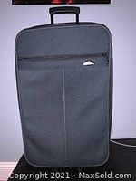 Dark green Samsonite suitcase upright showing front panel and extended telescoping handle